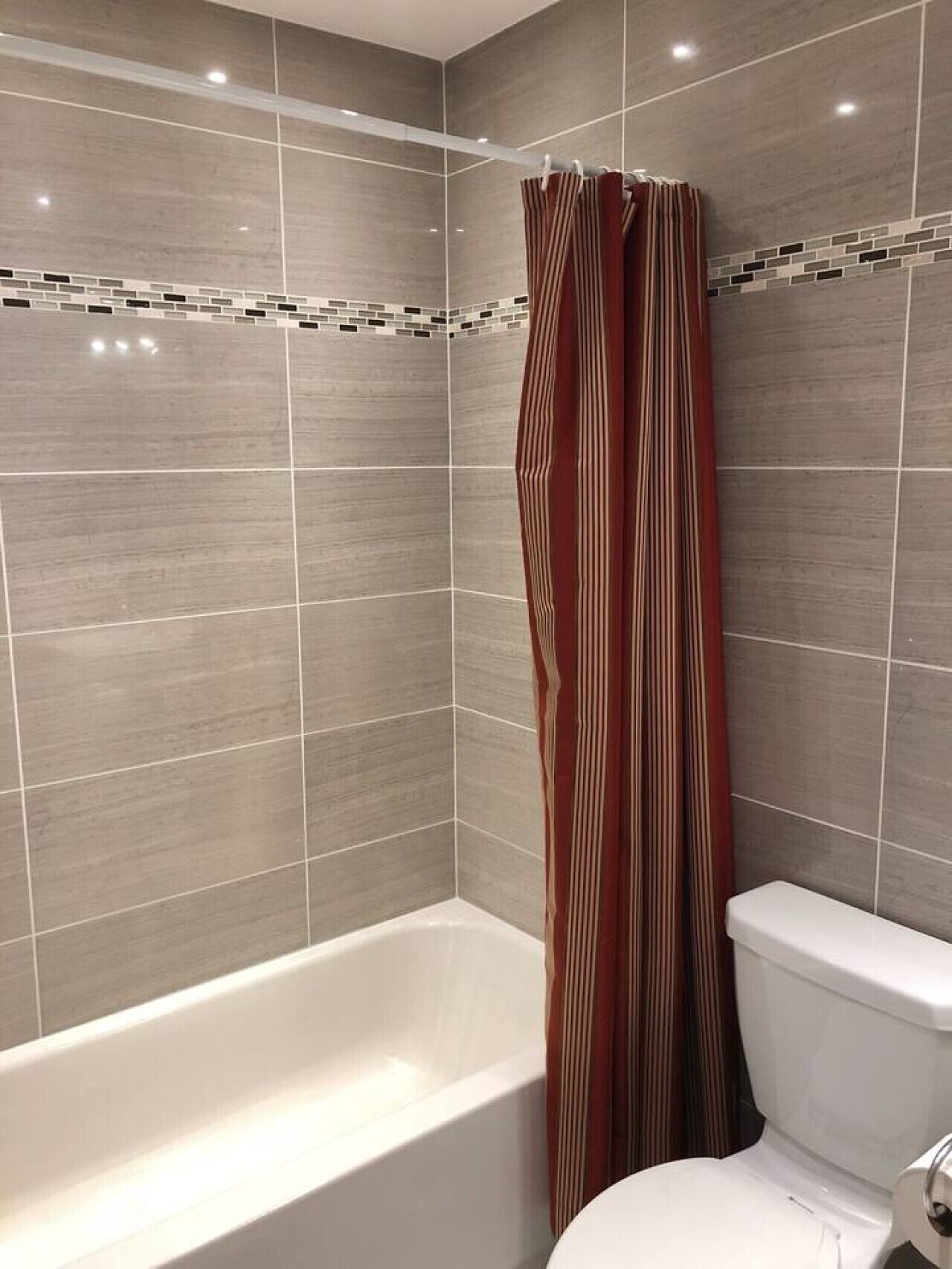 A bathroom with a bathtub, toilet, and shower curtain.