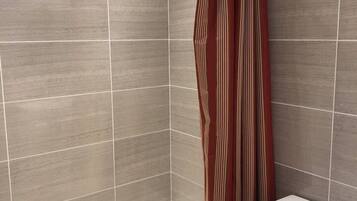 A bathroom with a bathtub, toilet, and shower curtain.
