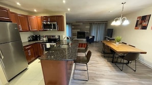 A modern kitchen with a central island, stainless steel appliances, and a dining area with a wooden table and chairs. - Whitetail Retreat-Hiking, Biking & River adventure (East Stroudsburg)