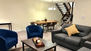 A living room with a sofa, armchairs, a coffee table, and a dining area with a table and chairs. - Whitetail Retreat-Hiking, Biking & River adventure (East Stroudsburg)