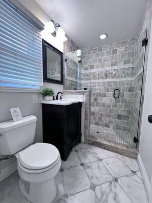 Une salle de bain comprenant des toilettes, un lavabo et un espace douche.
