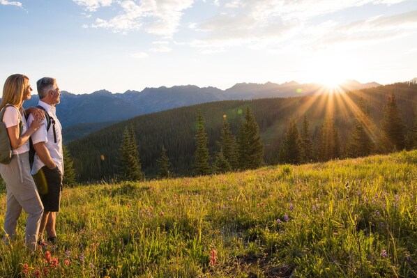 Ein Paar steht auf einer grasbewachsenen Anhöhe, im Hintergrund ein Gebirge.