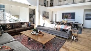Ein großzügiger Wohnbereich mit hoher Decke, einem Balkon und einem Essbereich.