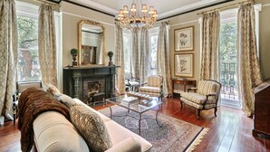 A spacious living room with a fireplace, comfortable seating, and large windows with curtains.