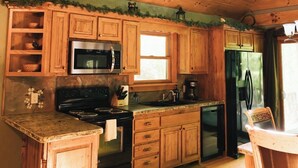 Un intérieur en bois comprenant un espace cuisine équipé d’une cuisinière, d’un four à micro-ondes et d’un réfrigérateur.