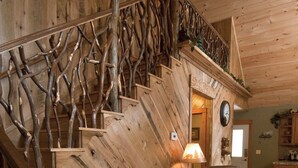 Un escalier en bois au design naturel, un canapé en cuir avec des coussins et une petite table agrémentée d’un objet décoratif.
