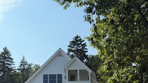 A white house with a porch, a staircase leading up to it, and a garden with various plants and shrubs. -  AIR-CONDITIONED Ocean Point OCEANFRONT with Lawn & Beach (Boothbay)