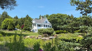 Una casa envoltada d'un jardí amb diverses plantes i flors.