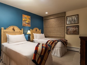Une chambre d’hôtel avec deux lits, un mur d’accent bleu et des œuvres d’art.