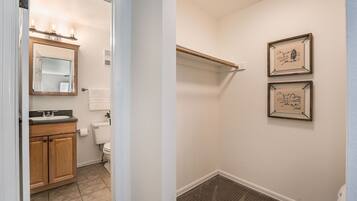A bathroom with a wooden vanity, a mirror, and a toilet. There are framed pictures on the wall.