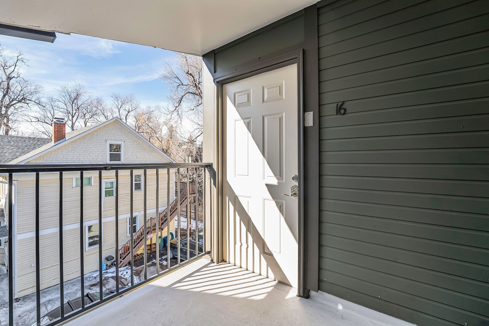 A balcony with a view of a neighboring house and a clear sky.