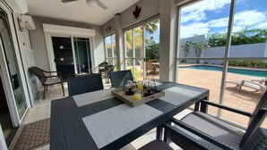 Un espace patio aménagé avec une table, des chaises et une vue sur la piscine.