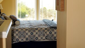 Un dormitorio con cama, ventana y estante fijado a la pared.