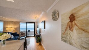 A modern living room with a view of the sea, a dining area, and a large painting on the wall. - Wow!!! Updated Beach Front Resort 3rd Fl Condo with amazing view. (Destin)
