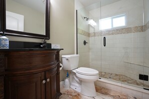 Enjoy a refreshing shower in the bathroom, featuring a glass-enclosed shower area, a large mirror, and a sink.