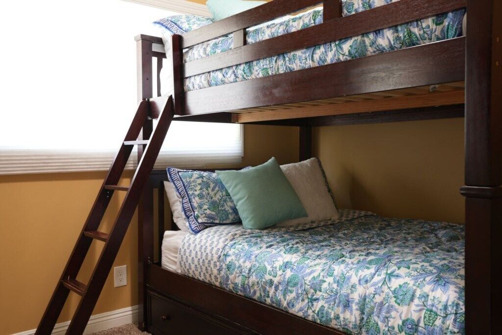 Uma cama beliche com escada, uma colcha florida e travesseiros.