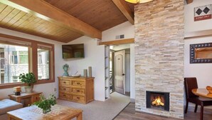 Ein gemütliches Wohnzimmer mit Kamin, Holzmöbeln und einer Wand aus Naturstein.