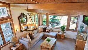 Ein gemütliches Wohnzimmer mit einem Ecksofa, einem Holztisch und einer Pendelleuchte.