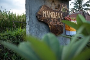 Une enseigne en bois portant le nom « MANDANA » et un élément décoratif.