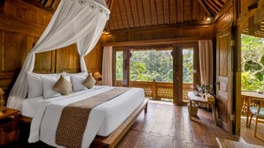A wooden bedroom with a canopy bed, large windows, and a view of the outdoors. - Mandana Ubud Villa (Ubud)