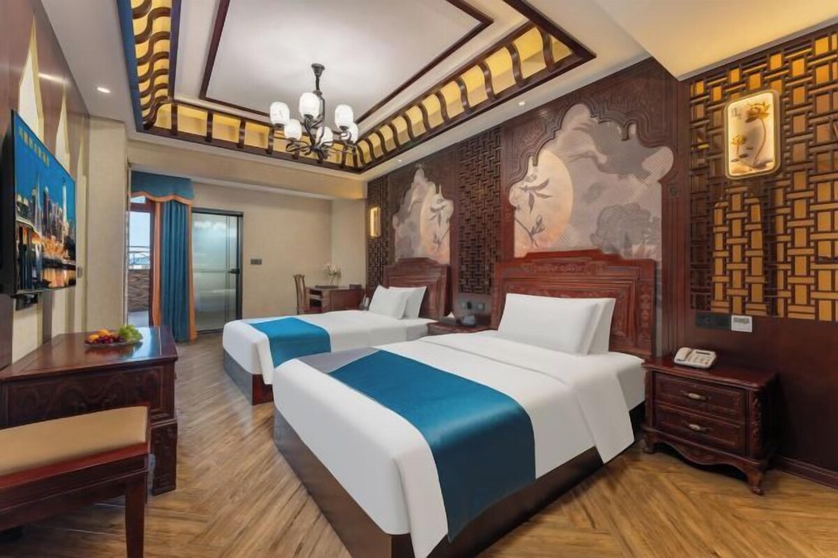 A hotel room with two beds, wooden flooring, a chandelier, and a decorative wall with a geometric pattern.