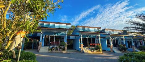 Un hotel con fachada azul, una entrada acogedora y un jardín bien cuidado.