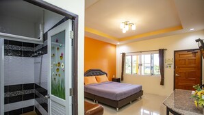 A hotel room with a shower, a bed with a headboard, a window with curtains, and a table with a vase of flowers. - Baan Suan  Meetang Resort (Chanthaburi)