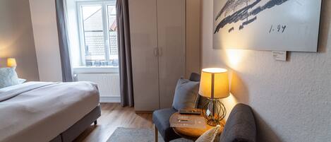 A modern bedroom with a bed, a sofa, a lamp, and a view of the outside.