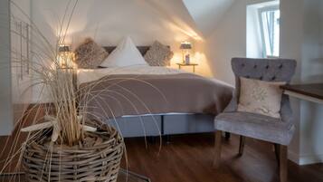 A bedroom with a bed, a chair, a nightstand, and a lamp.