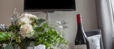 Una mesa con una botella de vino, una copa y un florero.