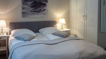 A neatly made bed with a grey headboard, two bedside tables with lamps, and a framed artwork above the bed.