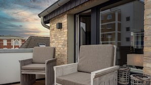 A balcony with two wooden chairs and a small table with candles. - Boutique Hotel Villa Monika (Sylt)