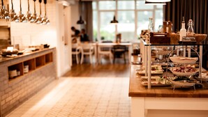 A buffet setup with various food items and condiments on a wooden counter. - Boutique Hotel Villa Monika (Sylt)