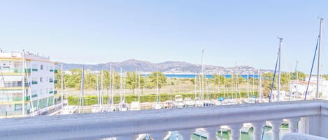 A balcony with a table set for breakfast overlooking a marina with boats and buildings.