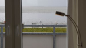 A view from a window overlooking a beach with a railing and a lamp.