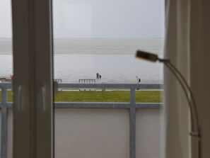 A view from a window overlooking a beach with a railing and a lamp. - A32 (BC.a5) - Stranddomicil Steiner (Büsum)