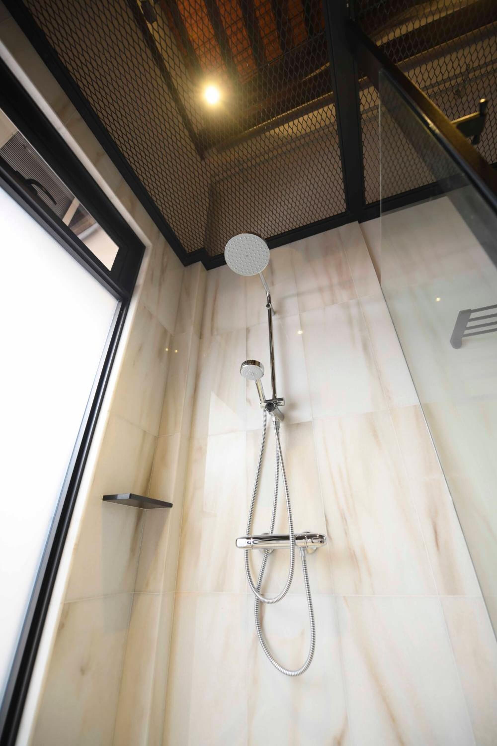 A modern shower with a handheld showerhead and a handheld hose.