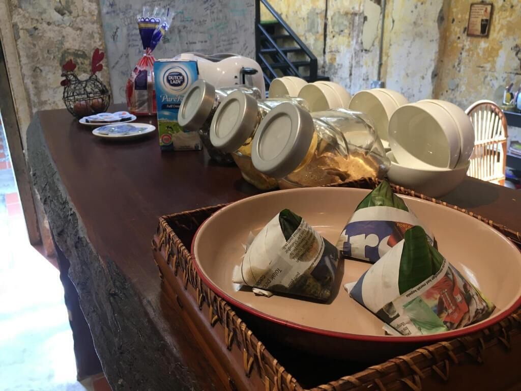 A kitchen counter with a variety of items including a Dutch Lady Pure Cream cheese, a bottle of blue liquid, and several glass jars.