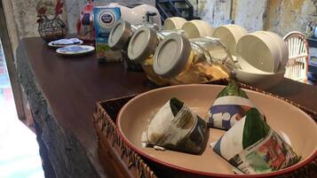 A kitchen counter with a variety of items including a Dutch Lady Pure Cream cheese, a bottle of blue liquid, and several glass jars.