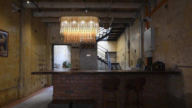 A bar area with a brick counter, two stools, and a hanging light fixture.