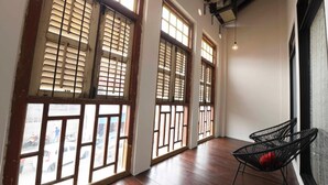 A room with large windows, wooden flooring, and black wireframe chairs.