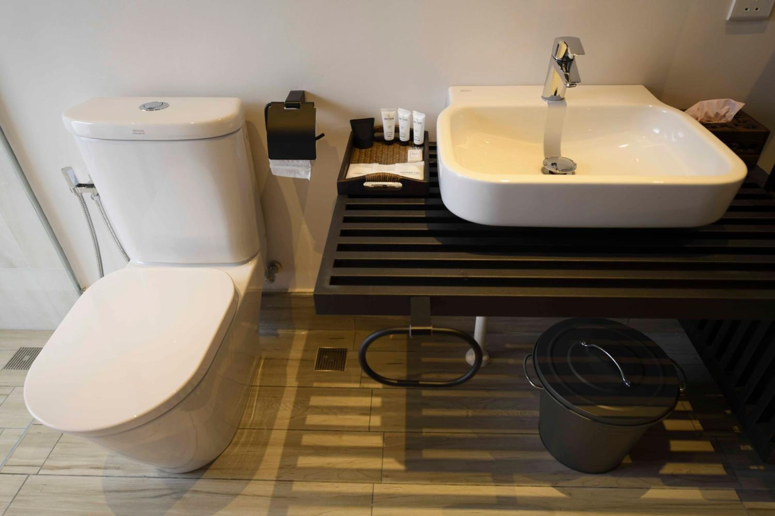 A modern bathroom with a toilet, sink, and a trash bin.