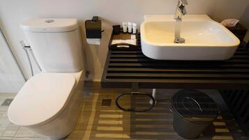 A modern bathroom with a toilet, sink, and a trash bin.