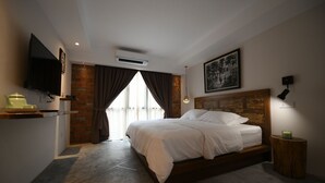 A modern bedroom with a large bed, a flat-screen TV, an air conditioning unit, and a brick wall.