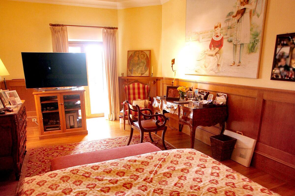Une chambre d’hôtel avec un grand lit, une télévision, un bureau avec une chaise et un tableau au mur.
