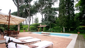 Un espace aménagé au bord de la piscine, avec des chaises longues, une table et un parasol.