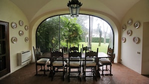 Un coin repas agrémenté d’une grande fenêtre en arc de cercle, d’une table dressée pour six personnes et d’une lanterne suspendue.