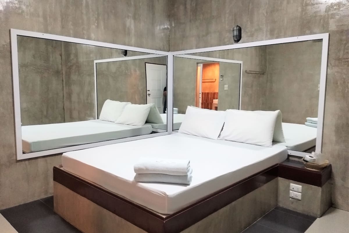 Une chambre d’hôtel moderne avec un grand lit, deux tables de chevet et un grand miroir.