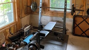 Un gimnasio con barra de dominadas, banco de pesas y diversos pesas.