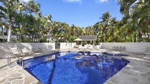 A swimming pool with lounge chairs and a covered seating area, surrounded by palm trees. - Kahala at Poipu Kai #121 By Parrish Kauai - walk to Poipu Beach & great for hone (Koloa)